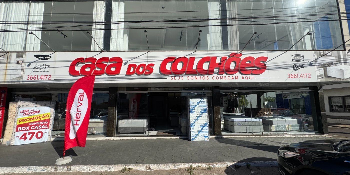 Vista frontal da loja Casa dos Colchões em Tramandaí, com colchões expostos na vitrine